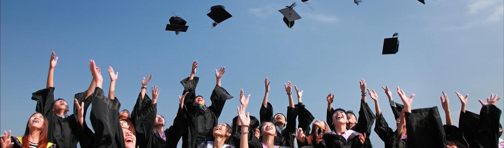 group of graduates tossing caps into the air group of graduates tossing caps into the air